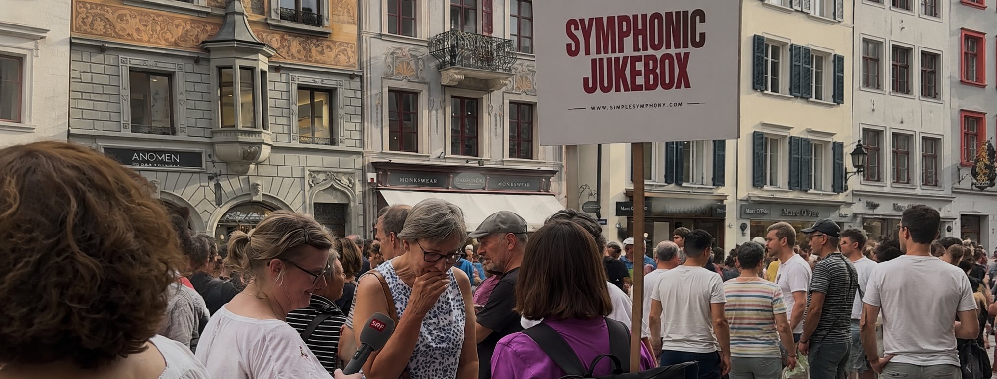 SRF interviewing a visitor in front of the Symphonic Jukebox sign in Lucerne's old town